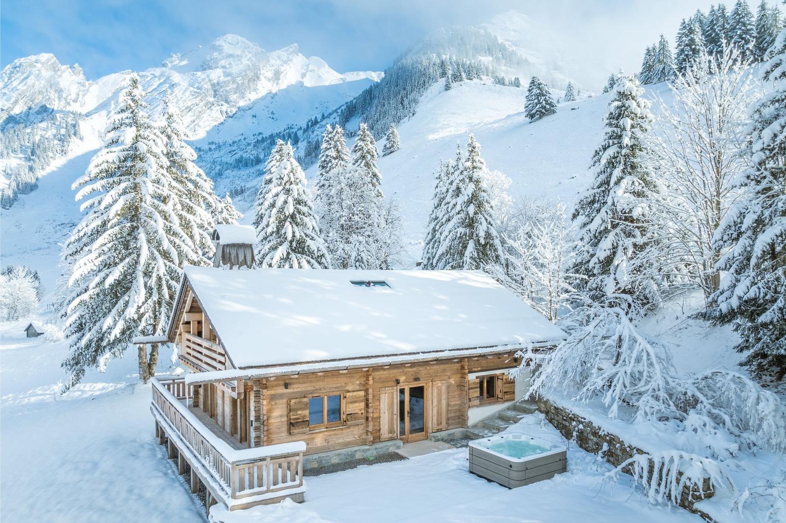 Chalet Aravis, an all-wood chalet in La Clusaz surrounded by snow-laden pines, with its outdoor hot tub