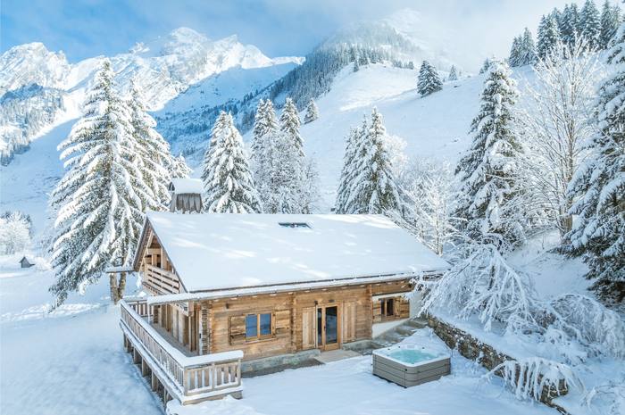 Chalet Aravis, an all-wood chalet in La Clusaz surrounded by snow-laden pines, with its outdoor hot tub