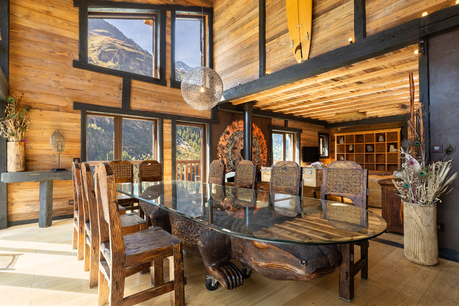 Chalet Hideaway's Balinese-inspired dining room in Tignes, with a hand-carved round table and tribal masks on teak walls