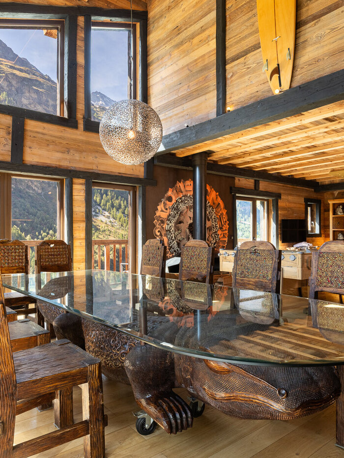 Chalet Hideaway's Balinese-inspired dining room in Tignes, with a hand-carved round table and tribal masks on teak walls