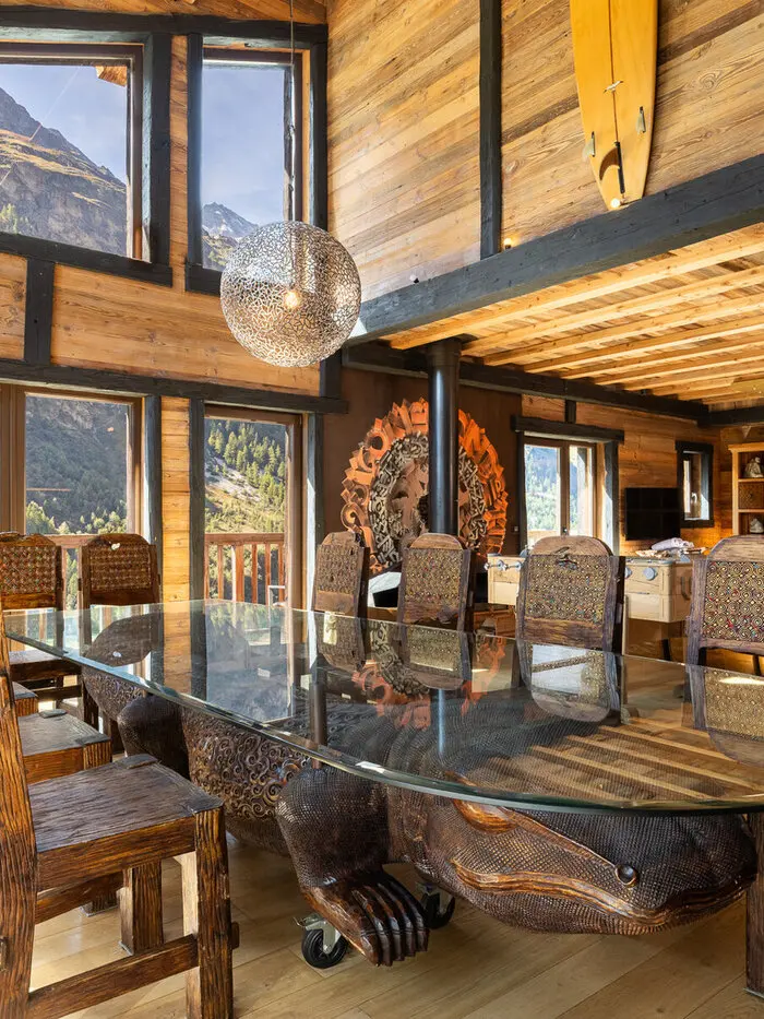 Chalet Hideaway's Balinese-inspired dining room in Tignes, with a hand-carved round table and tribal masks on teak walls