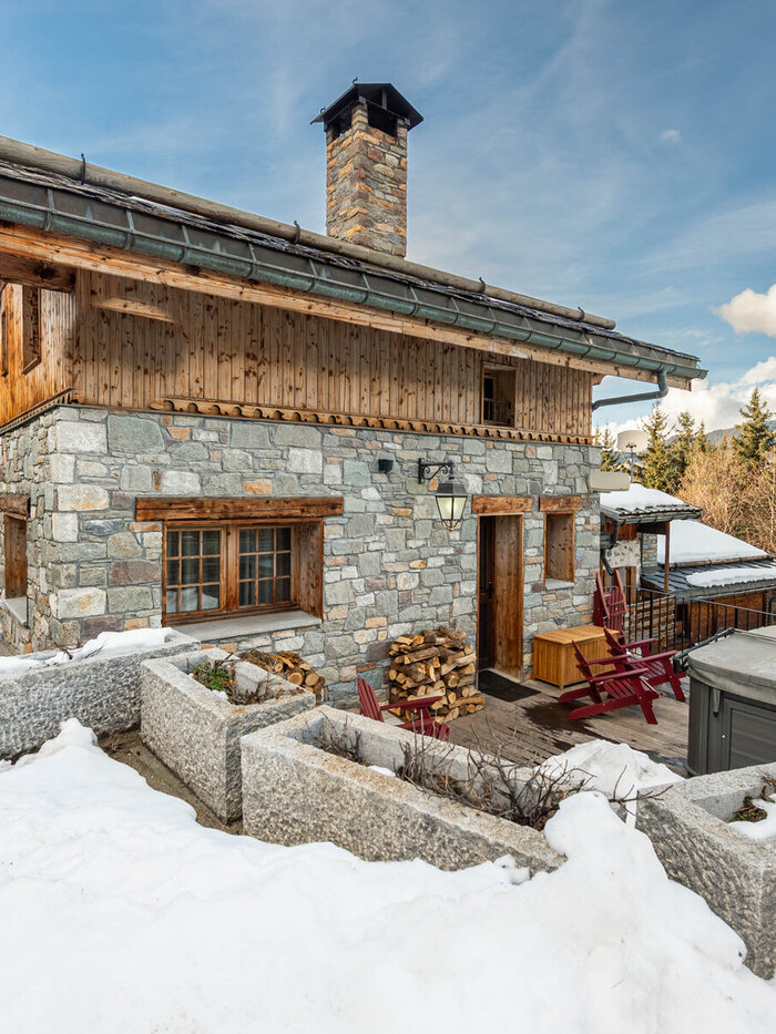 Chalet Ivory's stone-and-timber exterior in Courchevel, framed by snow-covered peaks