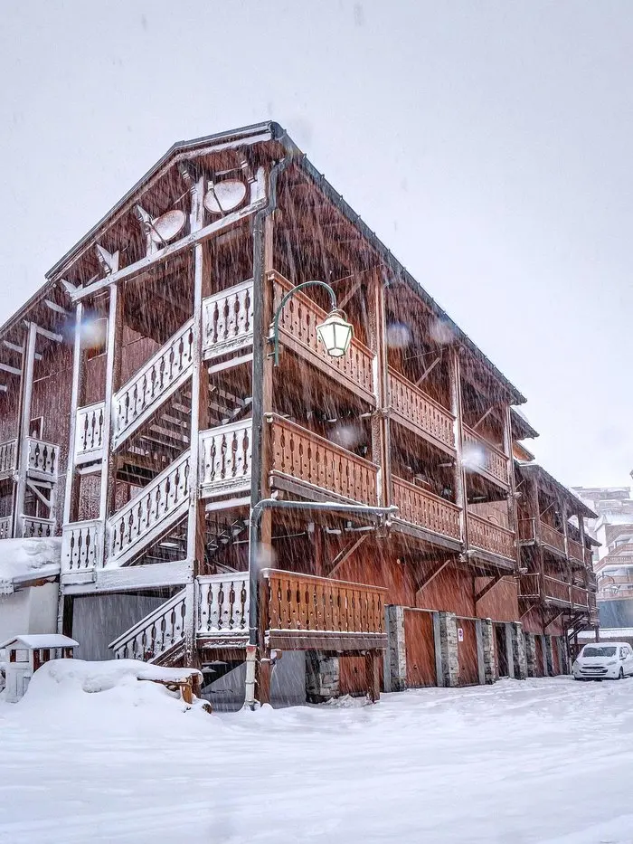 Chalet Solace's snow-covered timber exterior in Val Thorens during a winter storm