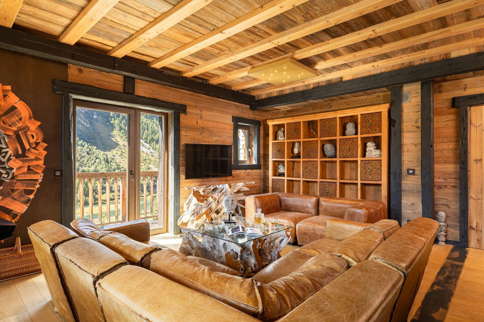 A chalet living room with leather sofas and mountain views